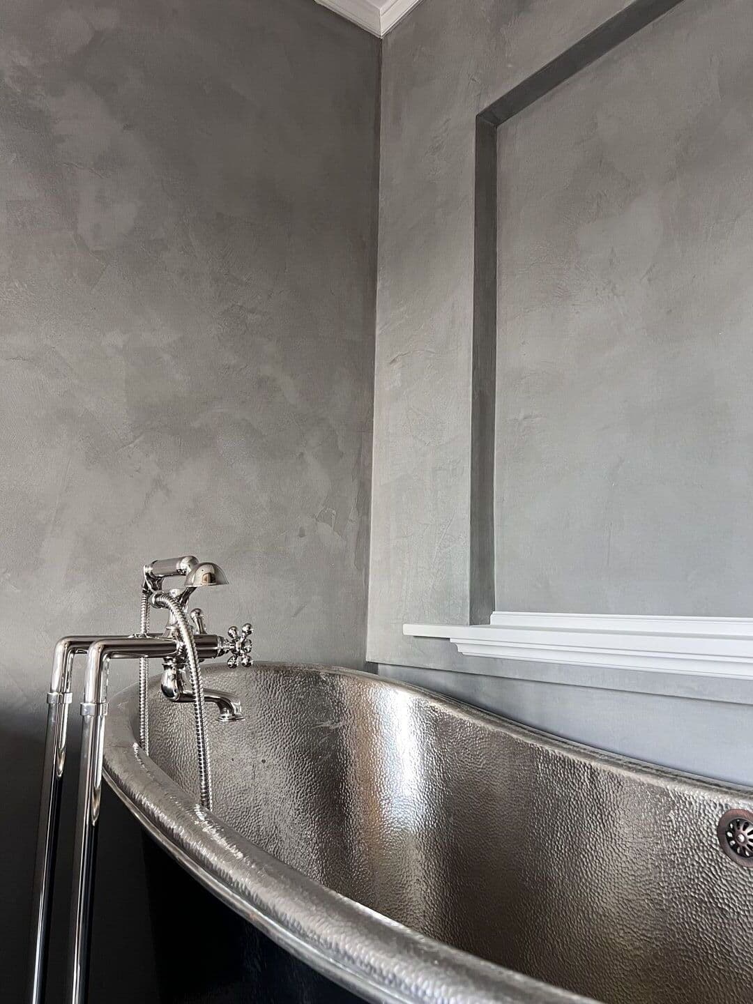 Tadelakt bathroom wall with polished silver bathtub