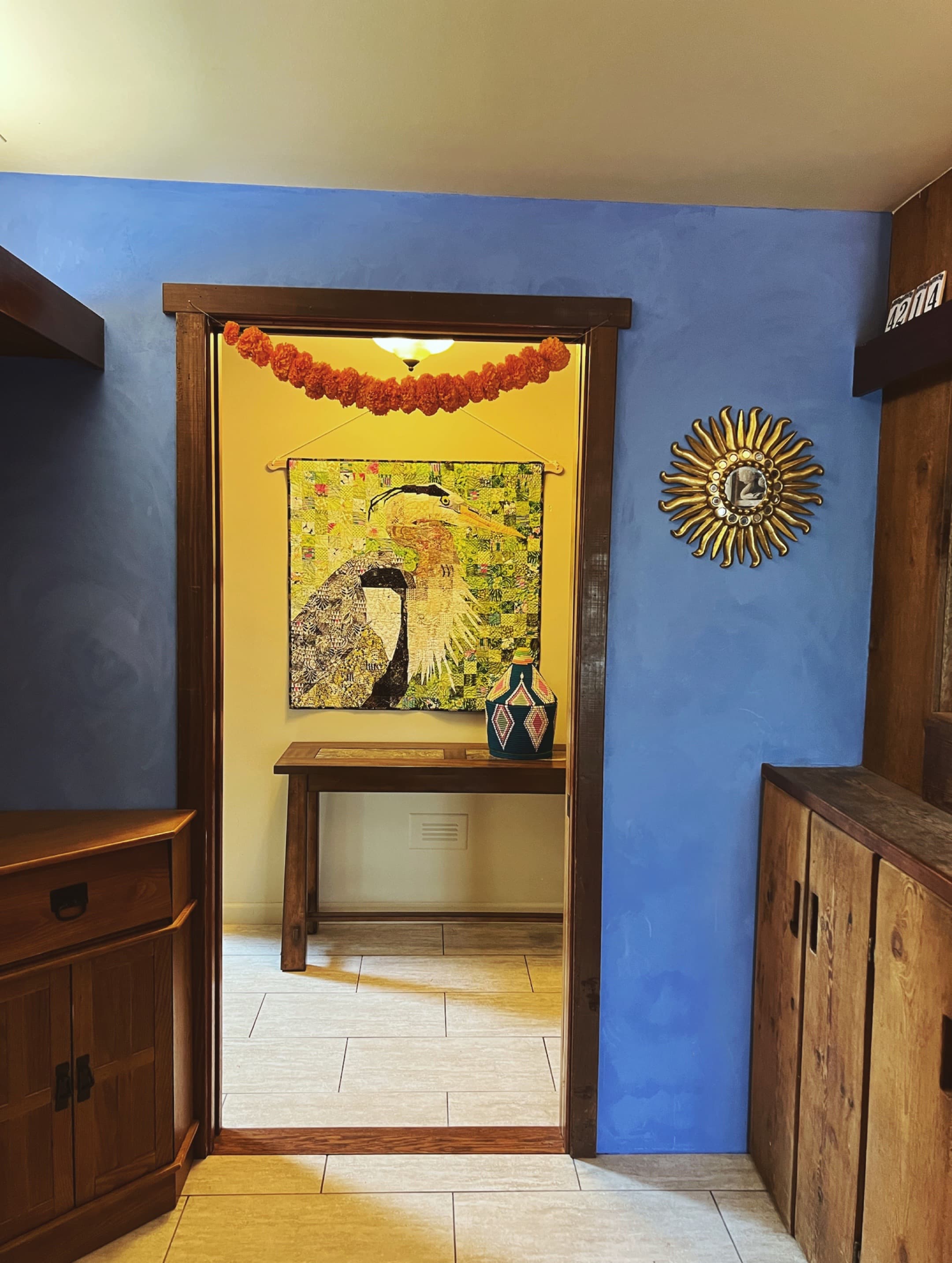 Blue plaster mudroom with gold sun mirror